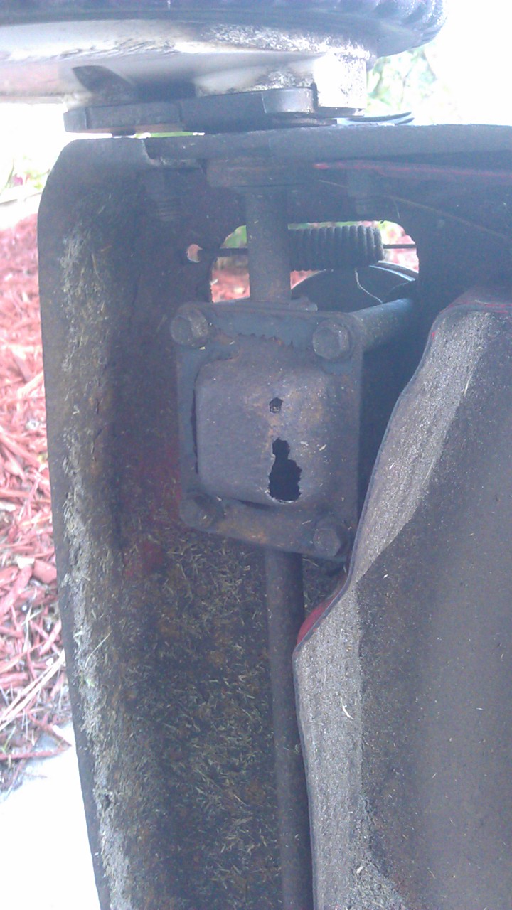 Close-up of a rusty lawnmower deck part with a hole