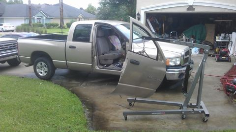 1994 Ford Bronco - A tan pickup truck is parked in a driveway with its doors open, and an engine hoist is attached to the front.