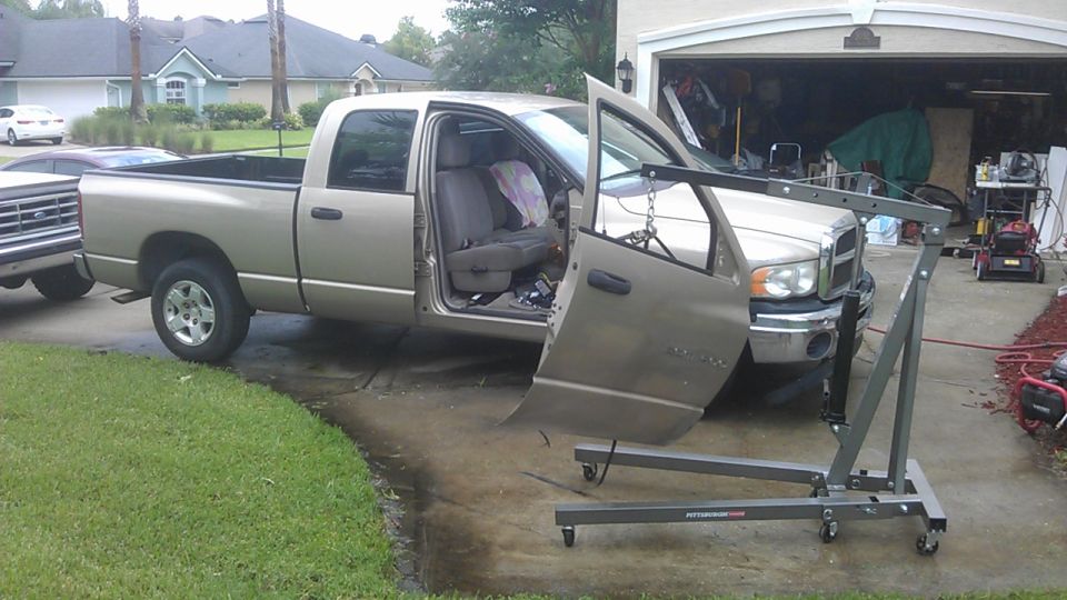 Tan pickup truck with driver's door open, engine hoist attached