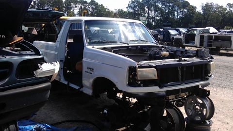 1994 Ford Bronco - This white 1994 Ford Bronco is seen in a junkyard with its hood open and missing several parts.