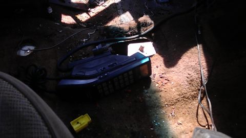 1994 Ford Bronco - The interior of a vehicle shows a car phone lying on the floor amidst debris.