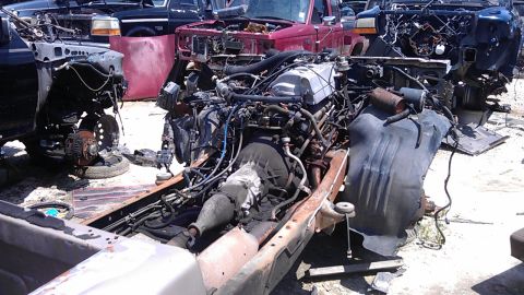1994 Ford Bronco - Dismantled vehicles and engines are visible in a junkyard setting.