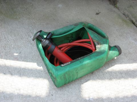 1994 Ford Bronco - Fluid transfer pump and hose stored in a green drain pan on a concrete surface.