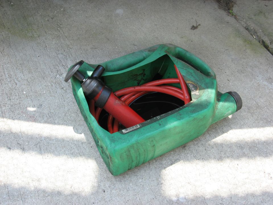 Green plastic drain pan with red fluid transfer pump and hose inside