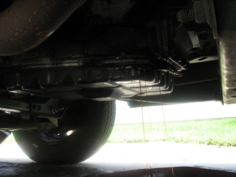 1994 Ford Bronco - Transmission fluid is draining from the pan of an unidentified vehicle.