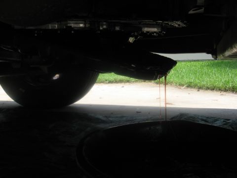 1994 Ford Bronco - Transmission fluid is being drained from a vehicle into a collection pan.