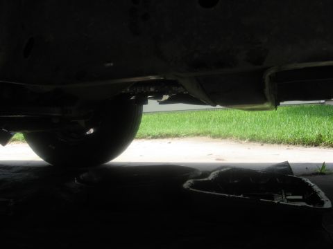 1994 Ford Bronco - Transmission fluid drain pan positioned under the undercarriage of a 1994 Ford Bronco.