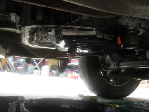 1994 Ford Bronco - Underside view of a vehicle's transmission and a tire, with a drip pan underneath.