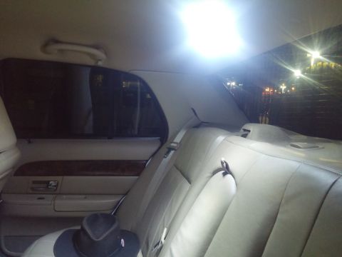 2000 Mercury Grand Marquis - The interior of a 2000 Mercury Grand Marquis is captured from the rear passenger side, revealing its tan leather upholstery and wood grain…