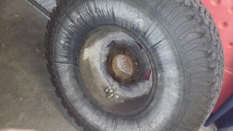 1996 Ford Bronco - Close-up of a worn tire and wheel, with lug nuts visible on the rusty rim.