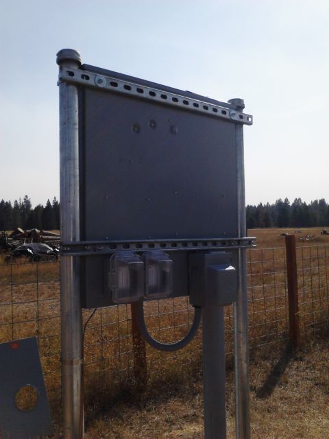 1989 Ford Bronco - An outdoor electrical panel is mounted on metal poles in a field, with a fence and trees in the background.