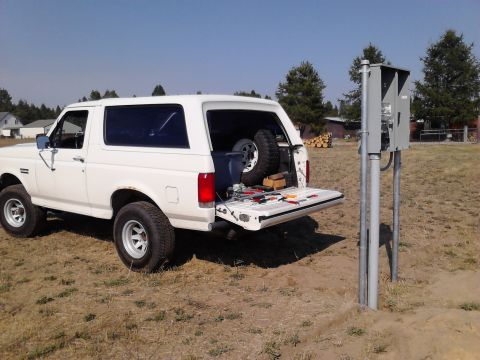 1989 Ford Bronco - White 1989 Ford Bronco parked outdoors with tailgate down, showing tools and a spare tire.