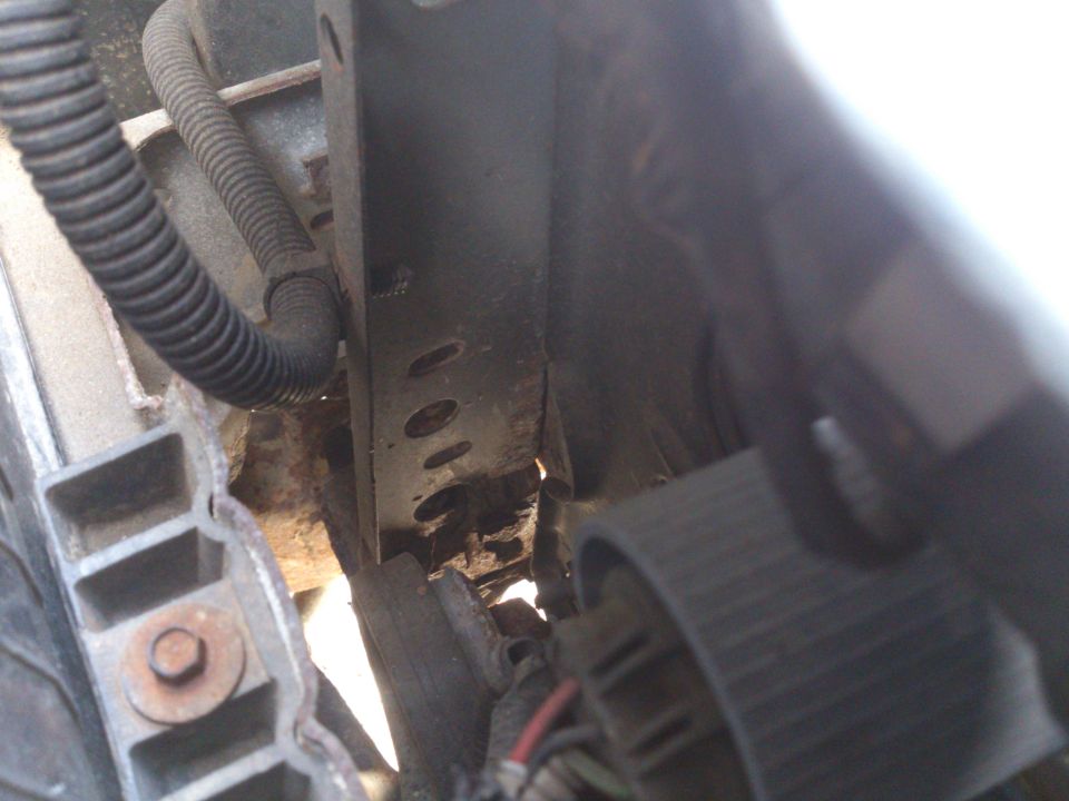 Close-up of rusty bracket, corrugated wire loom, and bolts in a 1995 Ford Bronco engine bay