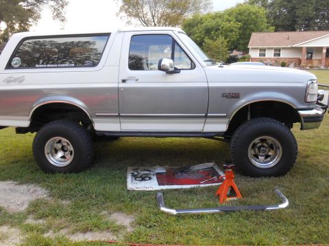 1994 Ford Bronco - Side view of a lifted Ford Bronco with its running boards laid out on the grass.