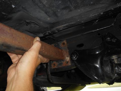 1994 Ford Bronco - Close-up of vehicle underbody, focusing on a rusty pipe and mounting bracket.