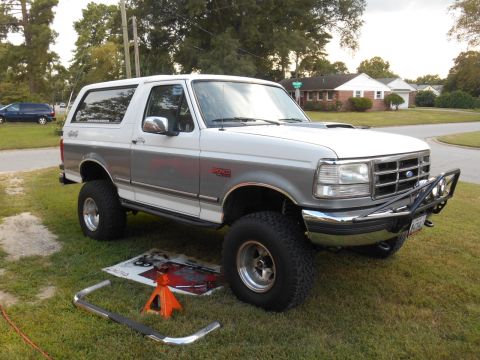 1994 Ford Bronco - This lifted Ford Bronco is parked on a grassy lawn with a residential street in the background.