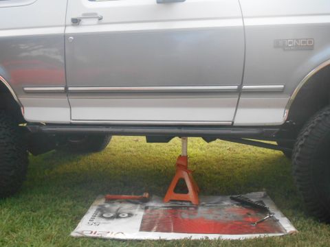 1994 Ford Bronco - A 1994 Ford Bronco is shown from the side, elevated by a jack with tools laid out on a mat.