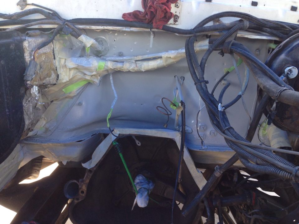 Engine bay with wiring harnesses and parts covered in tape and foil