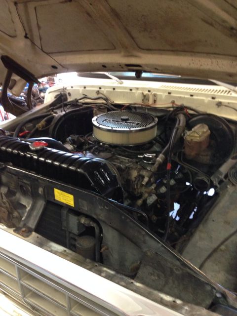 1978 Ford Bronco - The engine compartment of a vehicle is shown with the hood open, revealing the engine and its components.