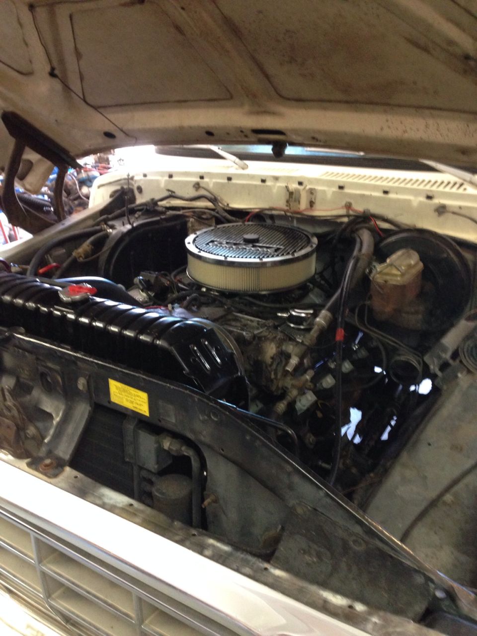 Engine bay with air filter, radiator, and brake fluid reservoir visible. Some wiring and hoses are present