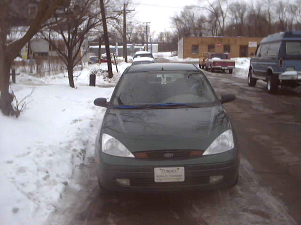 Dark green Ford Focus parked head-on along a snow-lined street in winter