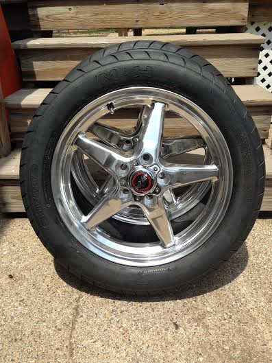2004 Ford Crown Victoria - A single chrome wheel and tire assembly is shown, resting on a concrete surface with wooden steps in the background.