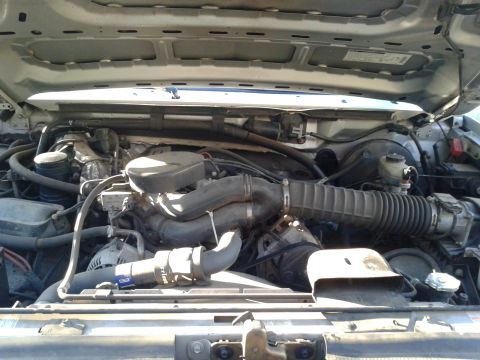 1996 Ford Bronco - View of the engine compartment, showing various hoses, the air intake system, and other engine components.