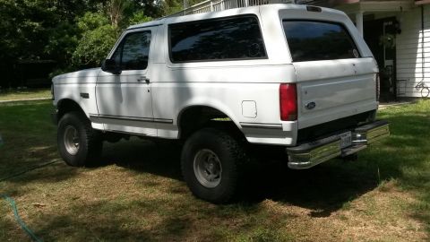 1996 Ford Bronco - A white 1996 Ford Bronco is parked on a grassy lawn next to a house.