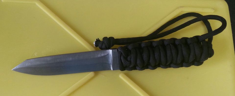 Knife with black paracord handle on yellow surface