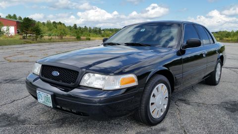 2001 Ford Crown Victoria - Black 2001 Ford Crown Victoria parked on asphalt with a building and trees in the background.