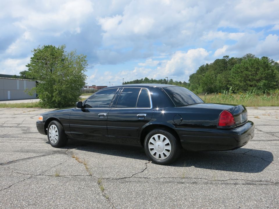 Black 2001 Ford Crown Victoria parked on cracked asphalt