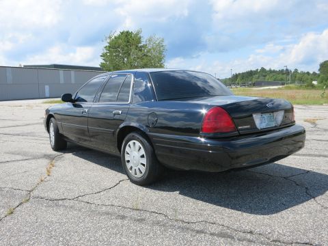 2001 Ford Crown Victoria - A black 2001 Ford Crown Victoria is parked outdoors on a cloudy day, viewed from the rear three-quarter angle.