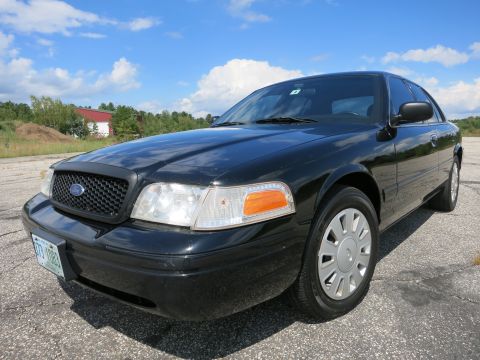 2001 Ford Crown Victoria - A black 2001 Ford Crown Victoria is parked on an asphalt surface under a partly cloudy sky.