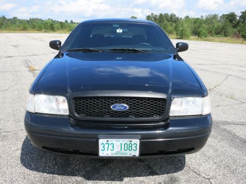2001 Ford Crown Victoria - Front view of a black 2001 Ford Crown Victoria parked on asphalt with trees in the background.