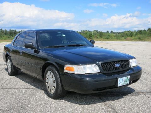 2001 Ford Crown Victoria - A black 2001 Ford Crown Victoria sedan is parked outdoors under a partly cloudy sky.