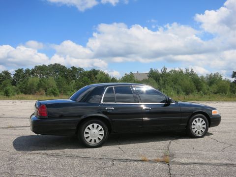 2001 Ford Crown Victoria - Side view of a black 2001 Ford Crown Victoria with tinted windows parked outdoors.