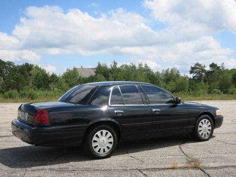 2001 Ford Crown Victoria - A black 2001 Ford Crown Victoria is parked outdoors under a partly cloudy sky.