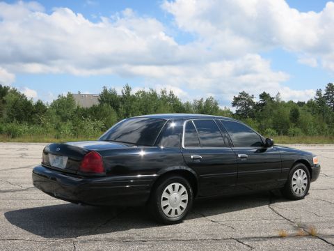 2001 Ford Crown Victoria - Rear three-quarter view of a black 2001 Ford Crown Victoria sedan on a paved lot.