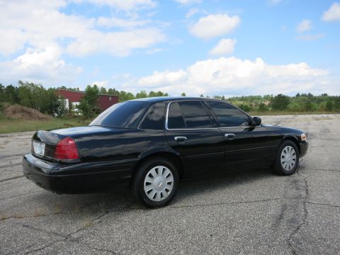 2001 Ford Crown Victoria - A black 2001 Ford Crown Victoria is parked outdoors under a partly cloudy sky.
