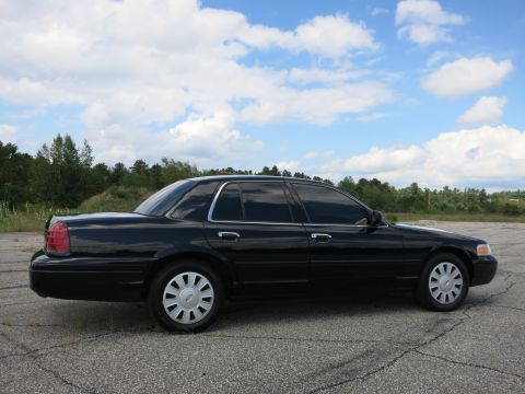 2001 Ford Crown Victoria - This black sedan is shown from the side under a partly cloudy sky.