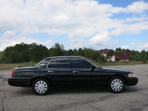 2001 Ford Crown Victoria - Side view of a black 2001 Ford Crown Victoria sedan parked outdoors under a cloudy sky.