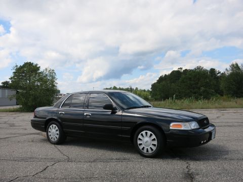 2001 Ford Crown Victoria - A black 2001 Ford Crown Victoria sedan is parked outdoors under a cloudy sky.