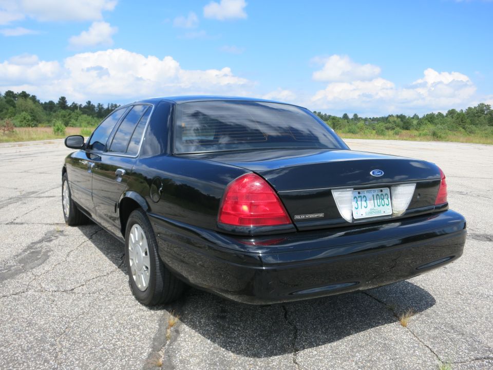 Black 2001 Ford Crown Victoria parked on asphalt, rear view. License plate reads 373-1083