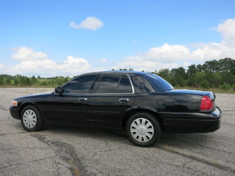 2001 Ford Crown Victoria - Side view of a black sedan parked outdoors on a cloudy day.