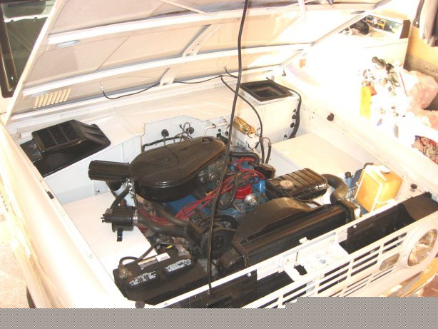 1967 Ford Bronco engine bay with hood open, showing engine, radiator, and battery
