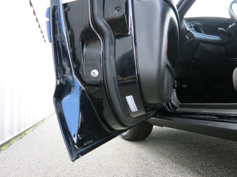 2001 Ford Crown Victoria - Close-up view of a black car's door jamb, revealing a white sticker and part of the interior.