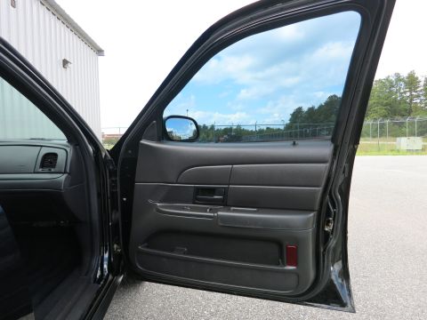 2001 Ford Crown Victoria - The interior door panel of a black car is shown with the door open, revealing the window and side mirror.
