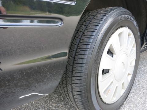 2001 Ford Crown Victoria - Side view of a car's tire and fender, with visible scratch on the body panel.