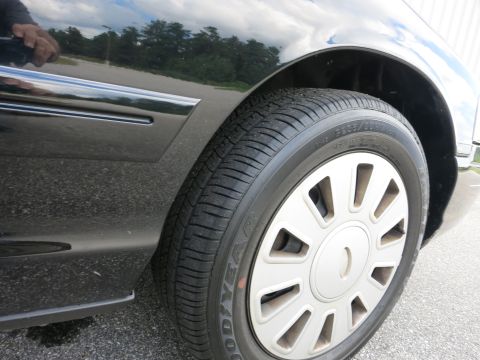 2001 Ford Crown Victoria - A close-up view of the side of a black vehicle, focusing on the wheel and fender area.