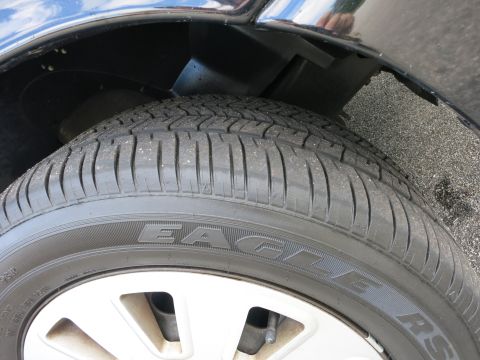 2001 Ford Crown Victoria - A close-up view of a tire and wheel well on a dark-colored vehicle.